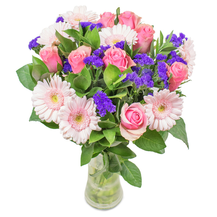 A strikingly elegant bouquet sits in a sleek clear glass vase, carefully arranged by experienced Northwood florists. Central to the display are approximately 7-9 delicate pink roses, their buds at varying stages of unfurling and showcasing timeless, spiral symmetry. Around them, 5-7 blush gerberas-distinguished by their rounded faces and pale cream-pink centres-add softness and visual balance, while vibrant, textured clusters of violette-hued statice bring dynamic contrast and a touch of wild beauty. Framing the flowers is an abundant foundation of deep green foliage, echoing the verdant scenery found in Northwood's parks and gardens. Crystal-clear water inside the vase accentuates the clean lines of each stem, highlighting the artistry and care poured into every local delivery. This bouquet, equally fitting for joyous occasions like Mother's Day or anniversaries, or as a daily reminder of beauty and care in a Northwood home or office, radiates a sense of celebration, affection, and refined craftsmanship-making it a truly memorable gift from your neighbourhood florist.